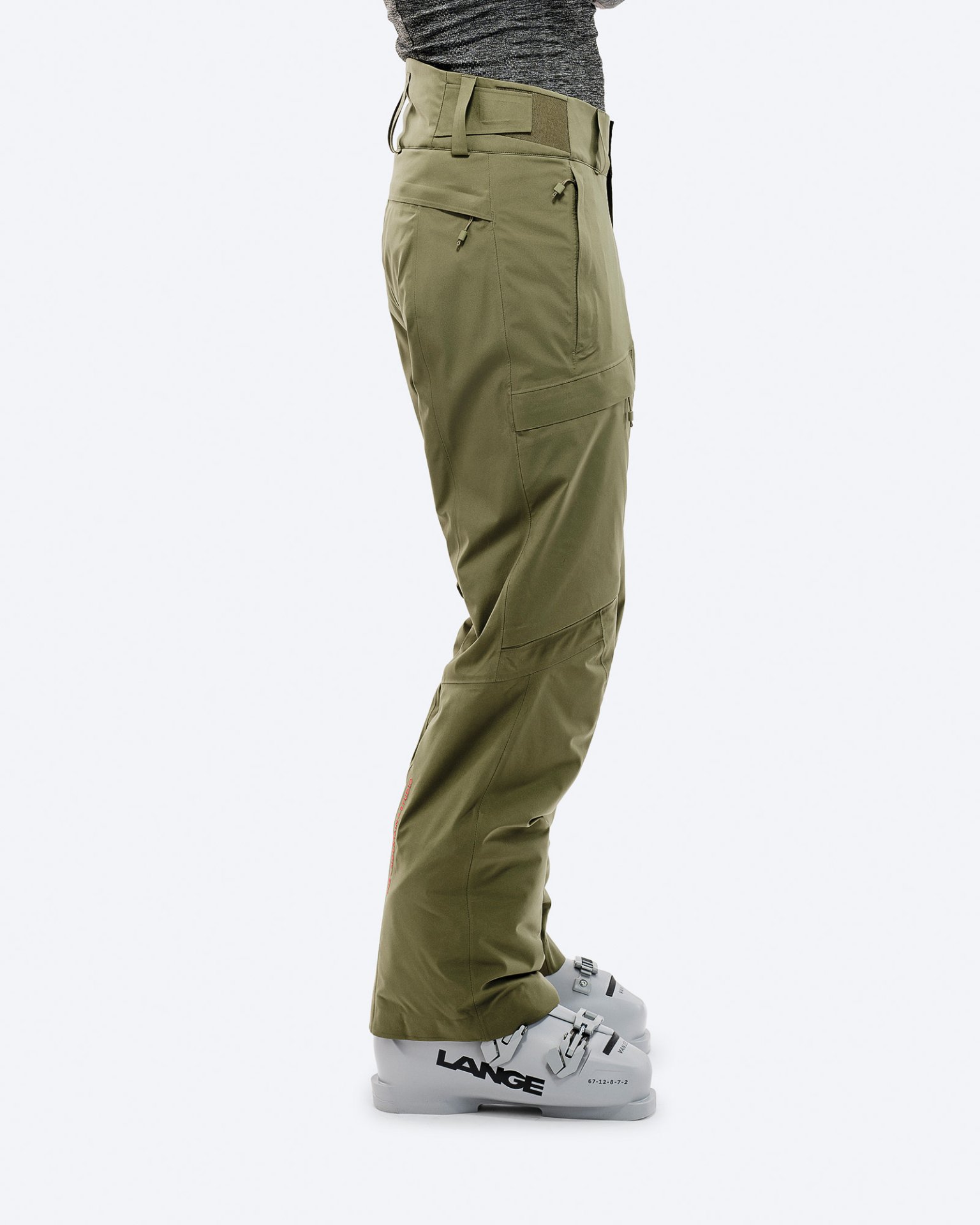 Person trägt Winter Moss GORE-TEX 2L Stretch Insulated Pants über Skischuhen vor weißem Hintergrund.