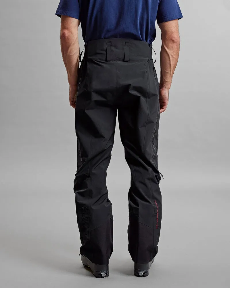 Rückansicht: Person mit schwarzer Y-1 HD GORE-TEX Pro 3L Shell Pant, Hose mit Reißverschlüssen und dezentem Markenlogo.