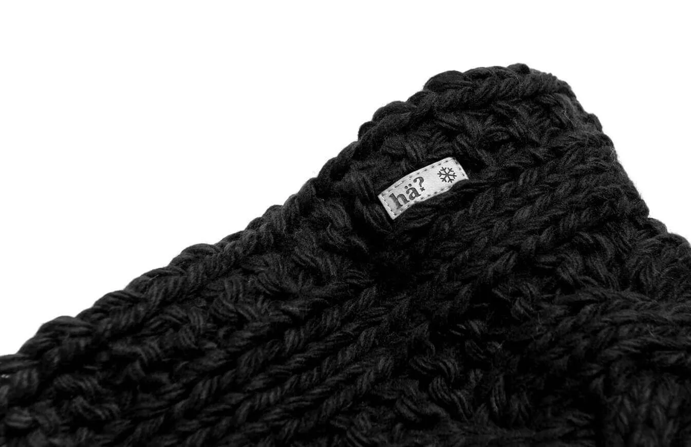 Detailaufnahme des schwarzen Stroller Neckwarmers mit Label und grobem Strickmuster.