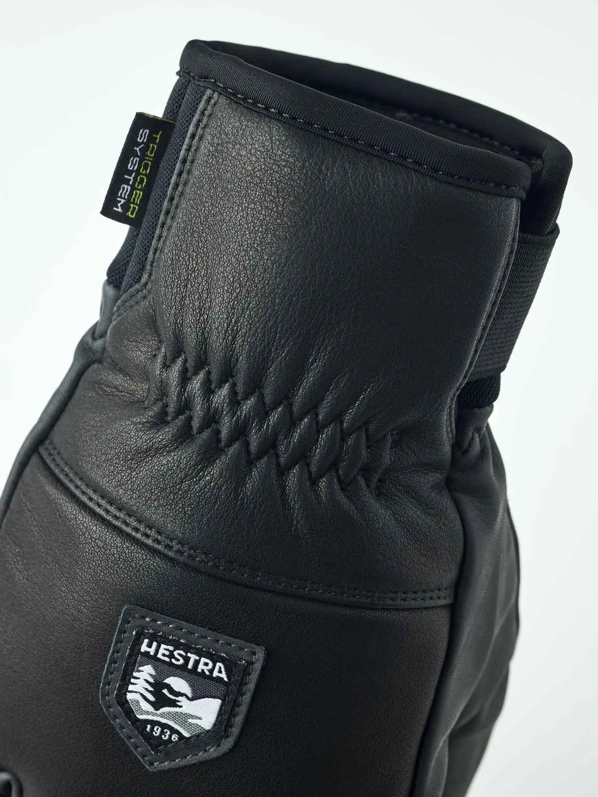 Detailaufnahme eines schwarzen Hestra Omni Trigger Handschuhs aus Leder mit Markenlogo.