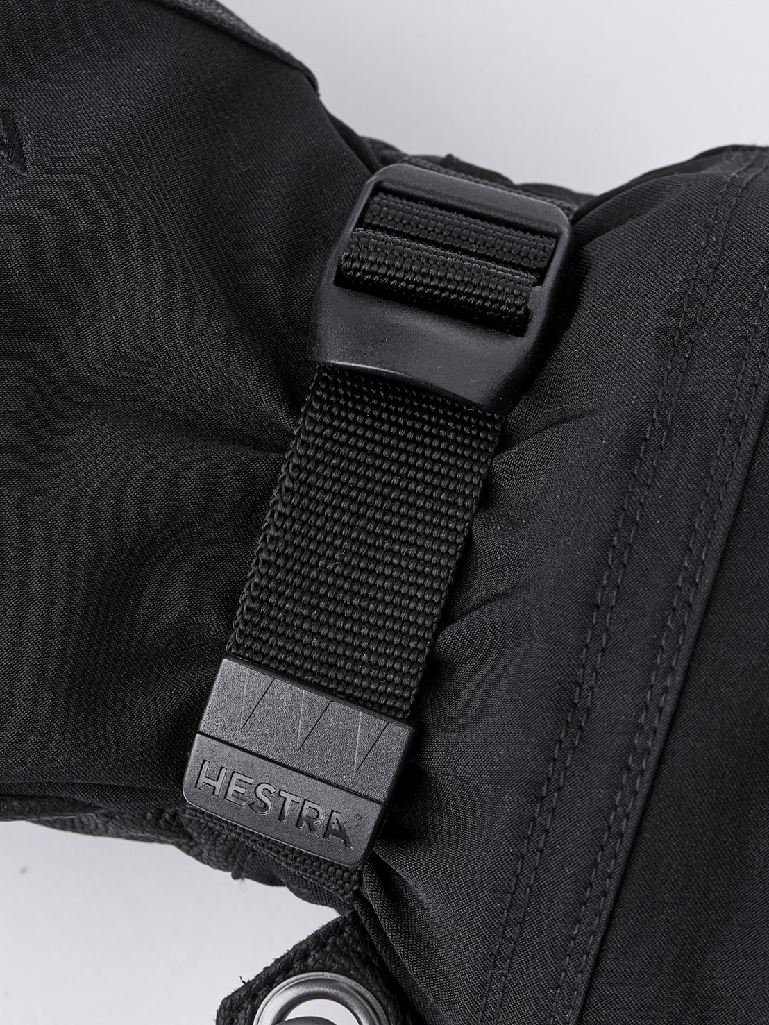 Hestra Army Leather Mitt Detailansicht eines schwarzen Hestra Army Leather Extreme Mitt mit Verschluss und Logo.