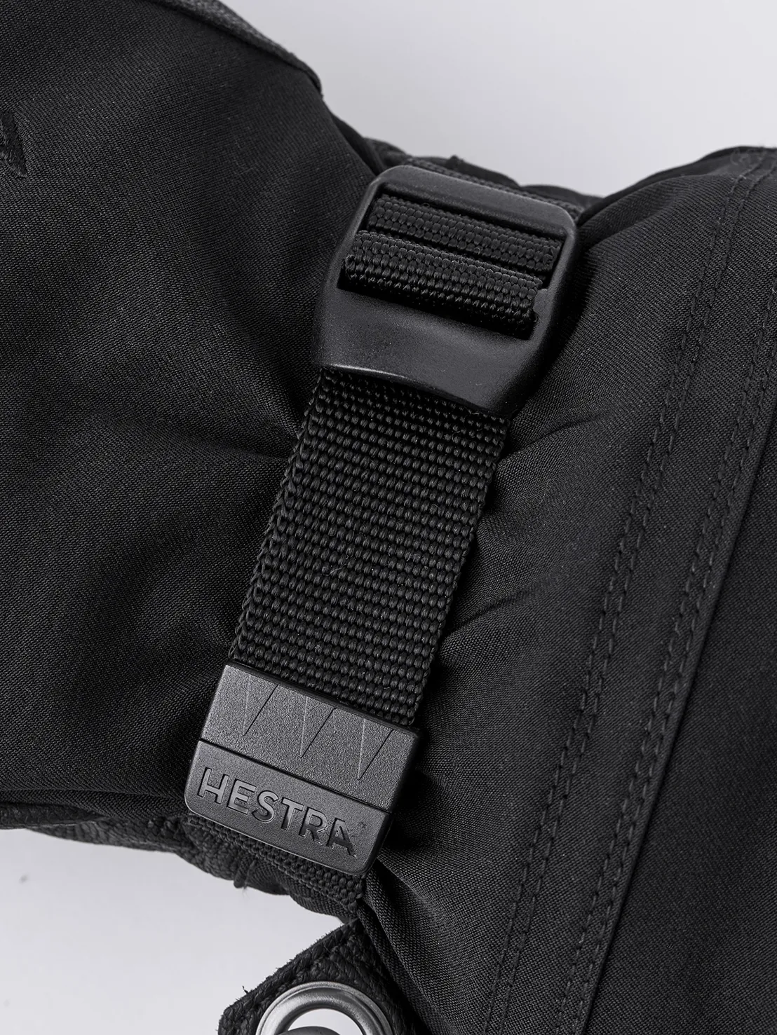 Detailansicht eines schwarzen Hestra Army Leather Extreme Mitt mit Verschluss und Logo.