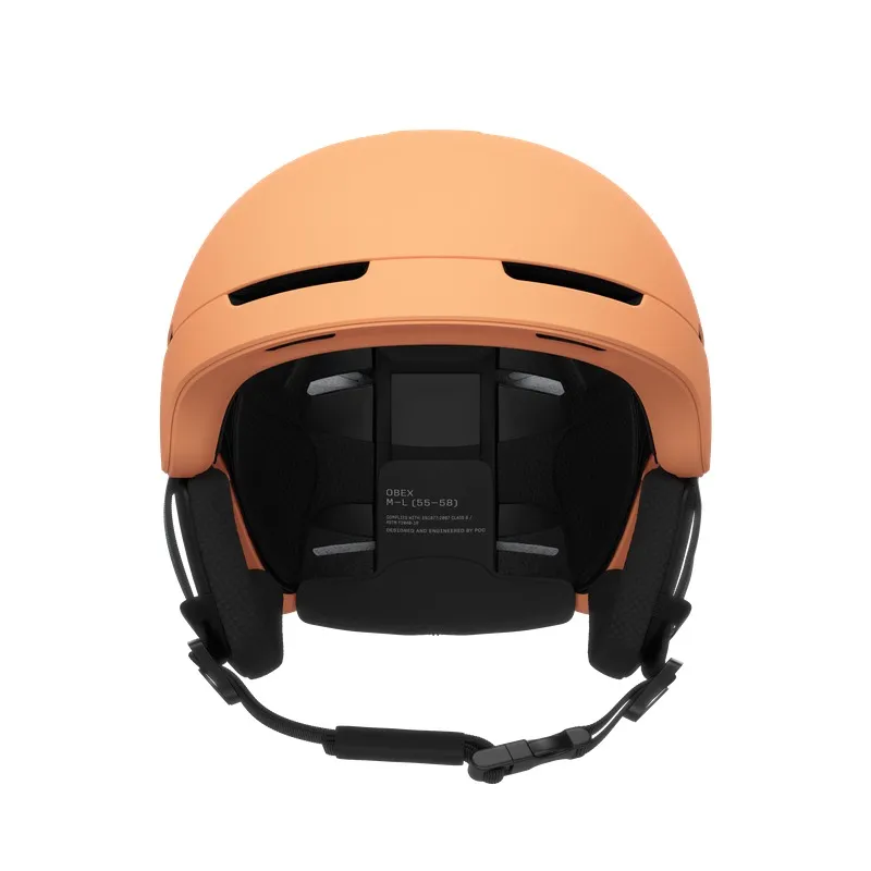 Pfirsichfarbener Skihelm von vorne, Kinnriemen und Ohrenschützer sind sichtbar.