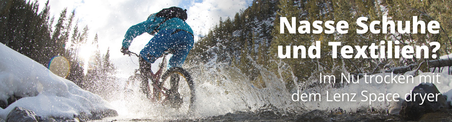 plb-space-dryer-DE Ein Mountainbiker fährt durch einen Bach, Wasser spritzt. Text: "Nasse Schuhe und Textilien? Im Nu trocken mit dem Lenz Space dryer".