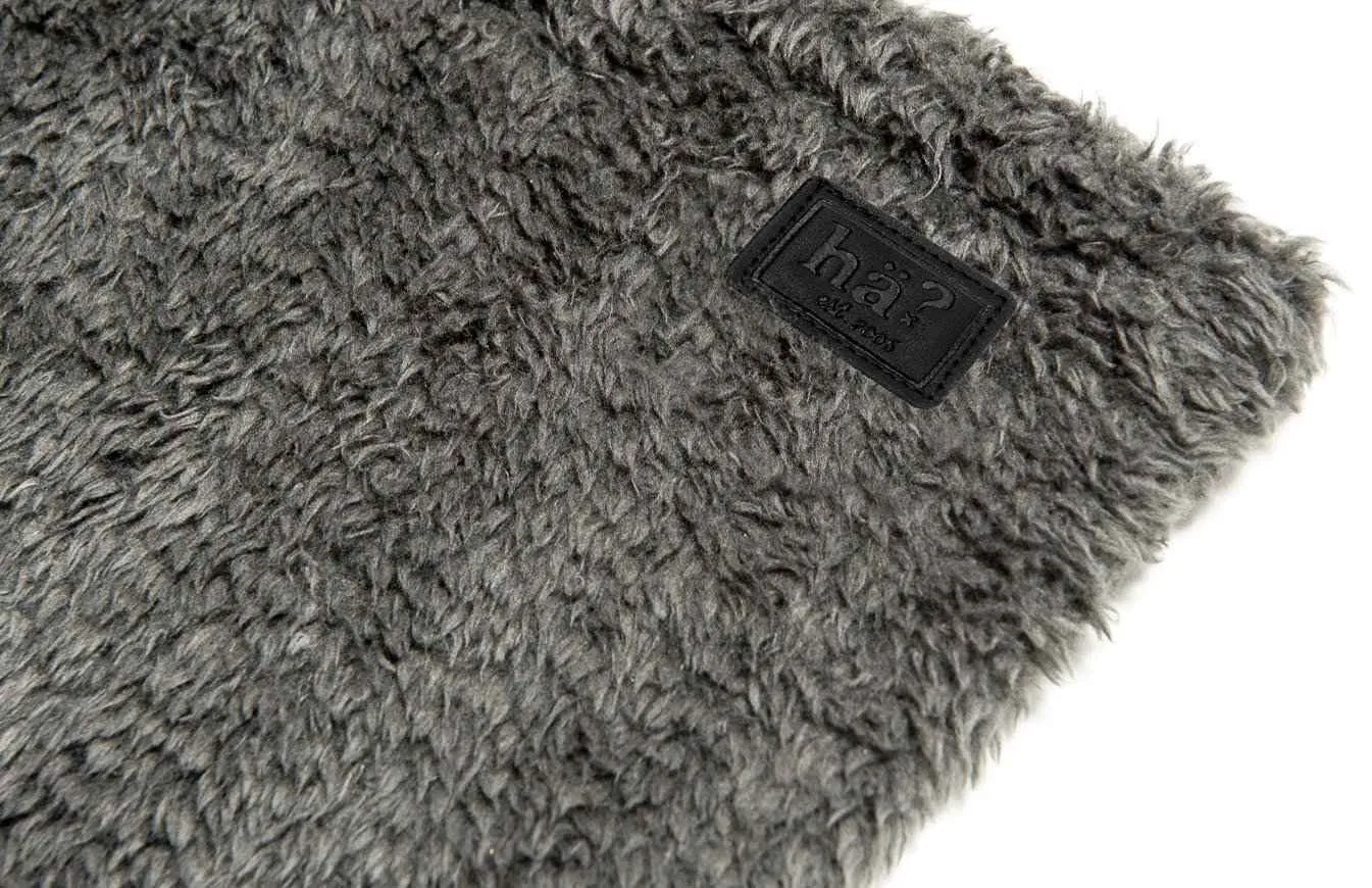 Detailaufnahme eines grauen Wellness Neckwarmers mit flauschigem Polar Fleece und Lederpatch mit Logo.
