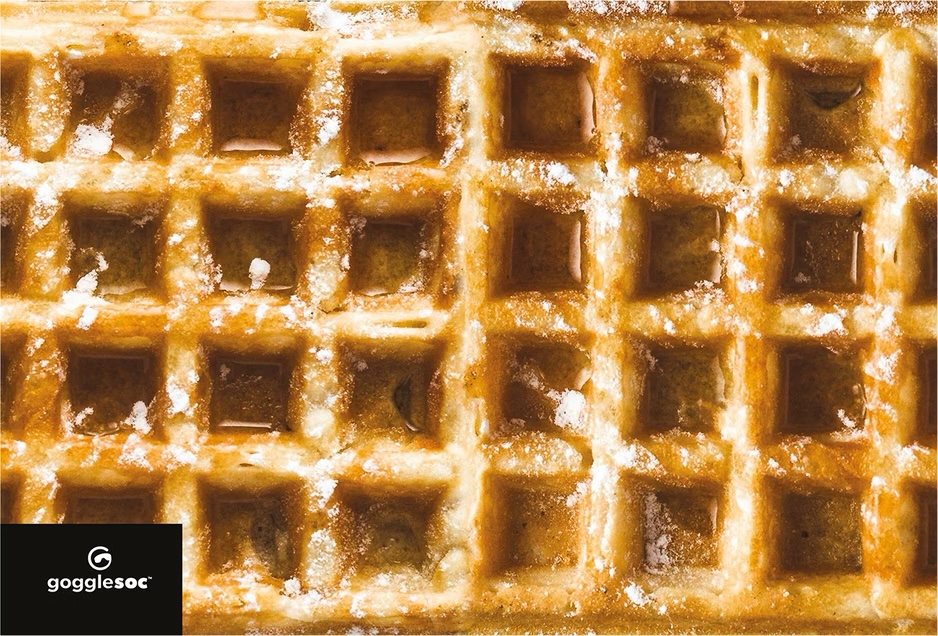 Waffel-Brillenputztuch Detailaufnahme einer Waffel mit Puderzucker. Waffel-Design für ein Brillenputztuch.