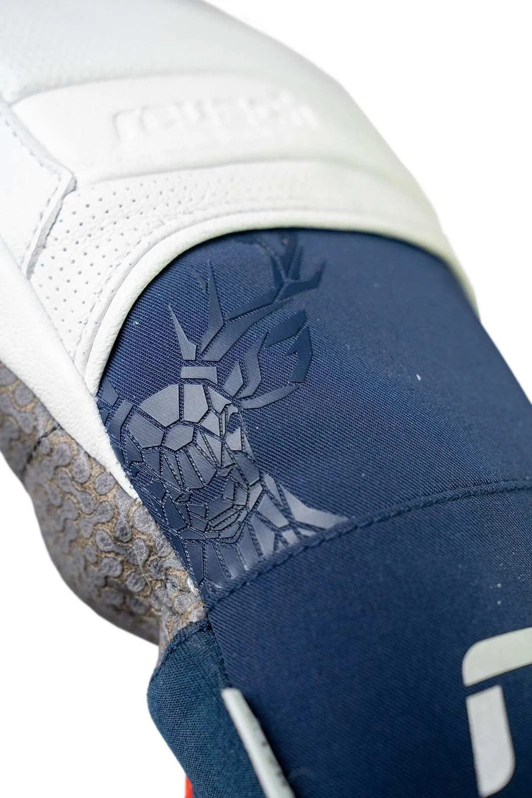 Nahaufnahme eines weißen und blauen Handschuhs mit einem stilisierten Hirschkopf-Emblem.