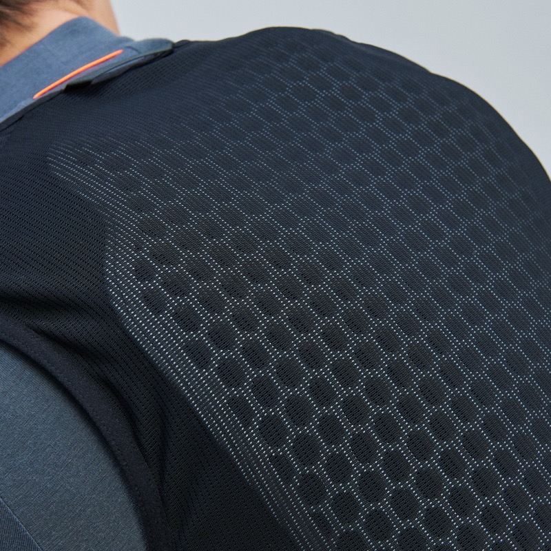 Detailansicht der POC VPD Air Vest in Schwarz mit wabenförmiger Struktur am Rücken, getragen über einem Hemd.