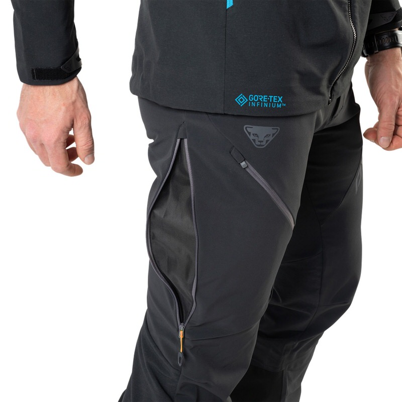 Nahaufnahme der schwarzen Dynafit Radical Infinium Hybrid Hose für Herren, mit Reißverschlüssen und Gore-Tex Infinium Logo.