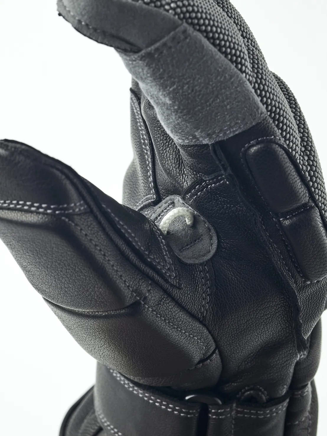 Nahaufnahme eines schwarzen Lederhandschuhs, der eine Hand darstellt. Details wie Nähte und Texturen sind sichtbar.