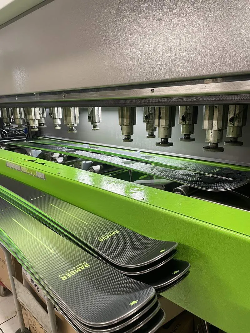 Wintersteiger Mercury mit Ski in der Maschine, davor ein Stapel Ramser Ski in der Werkstatt