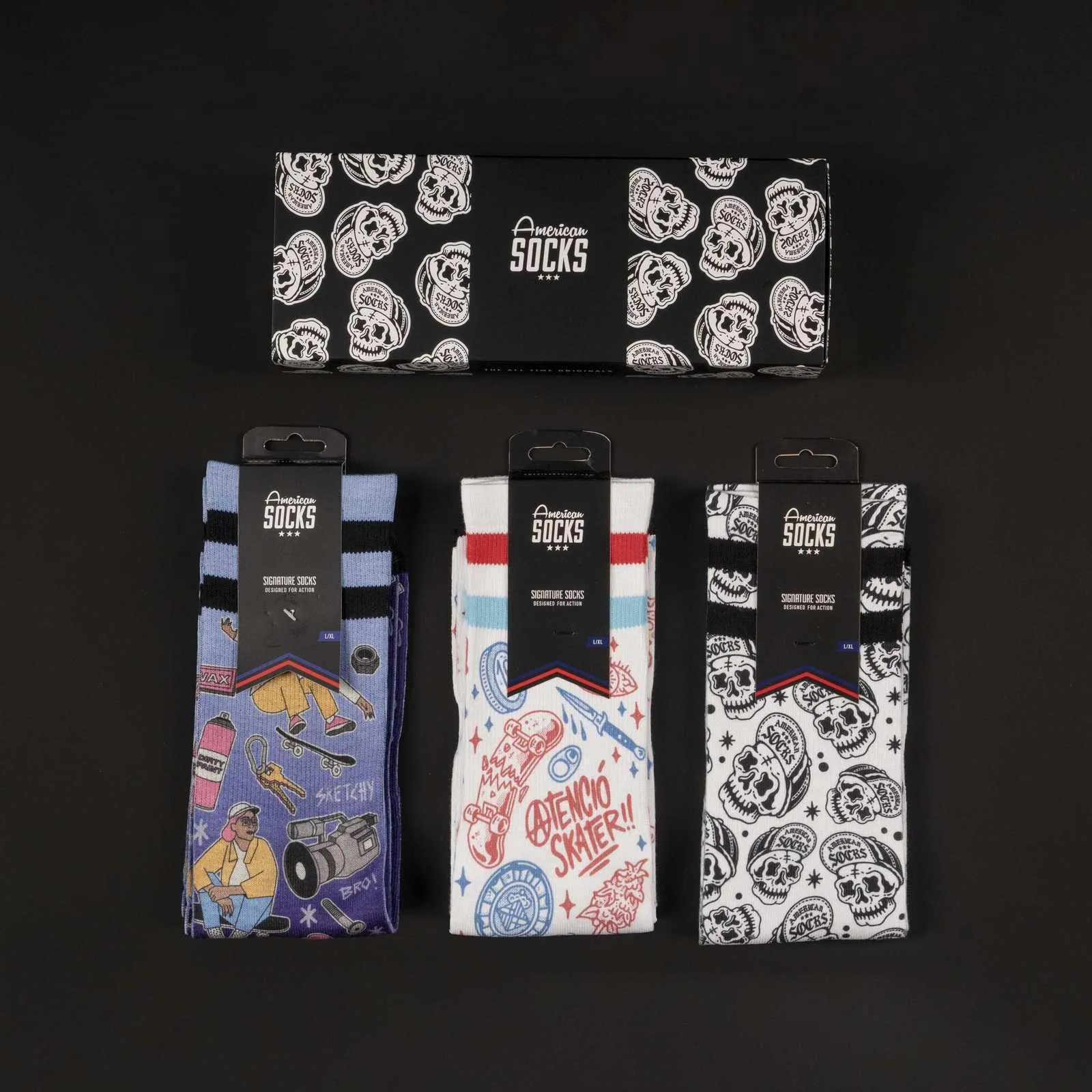 Drei Paar American Skater Socks mit Motiv, verpackt in Geschenkbox, auf schwarzem Grund.