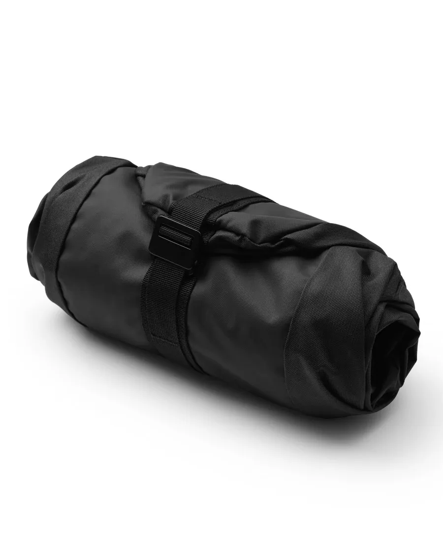 Eine gerollte, schwarze Db Snow Essential Skitasche mit einem schwarzen Riemen in der Mitte.