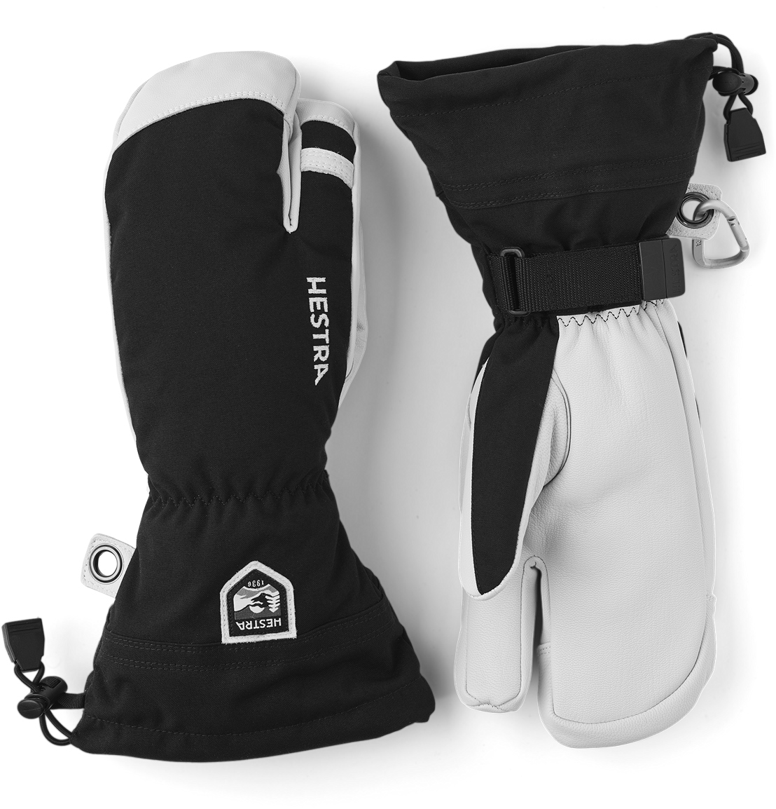 Hestra Ski-Handschuhe Zwei Hestra Ski-Handschuhe, ein 3-Finger-Modell, in Schwarz und Weiß, liegen nebeneinander auf weißem Untergrund.