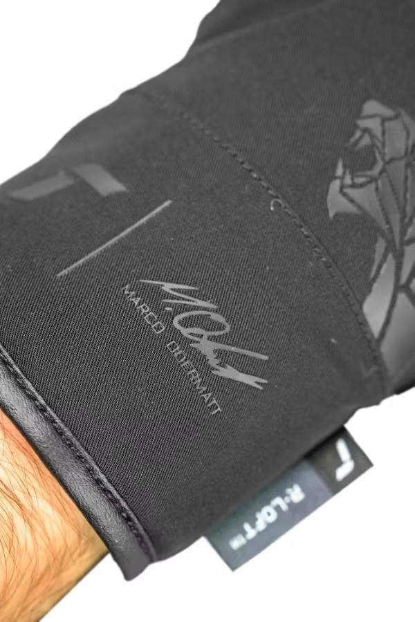 Marco Odermatt Handschuh Detailaufnahme eines schwarzen Handschuhs mit Lederbündchen. Darauf ein Logo, der Schriftzug "Marco Odermatt" und ein Etikett mit "R-LOFT".