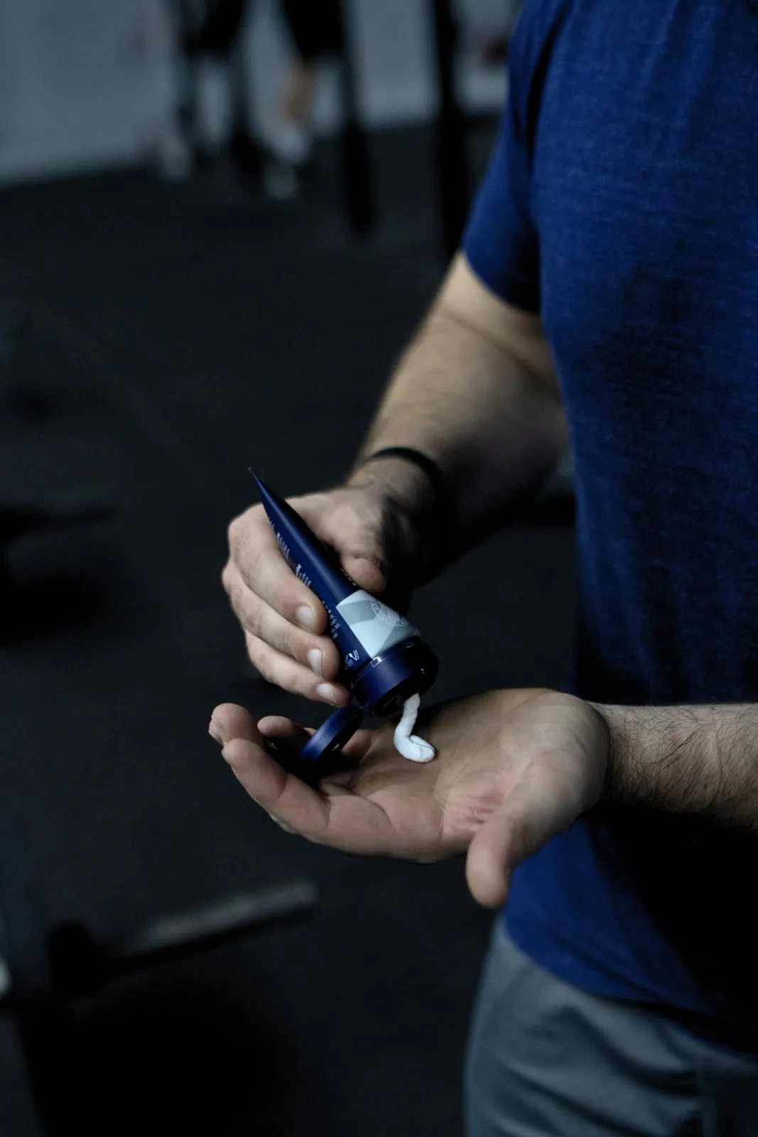 Mann drückt SPORT LAVIT Super Grip in die Hand. Tube blau-weiß mit weißer Creme.