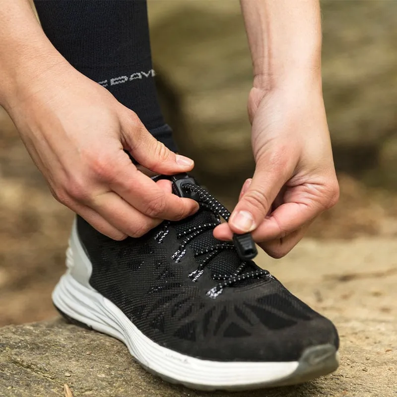 Zwei Hände bedienen ein Run Laces Schnürsystem an einem schwarzen Laufschuh.