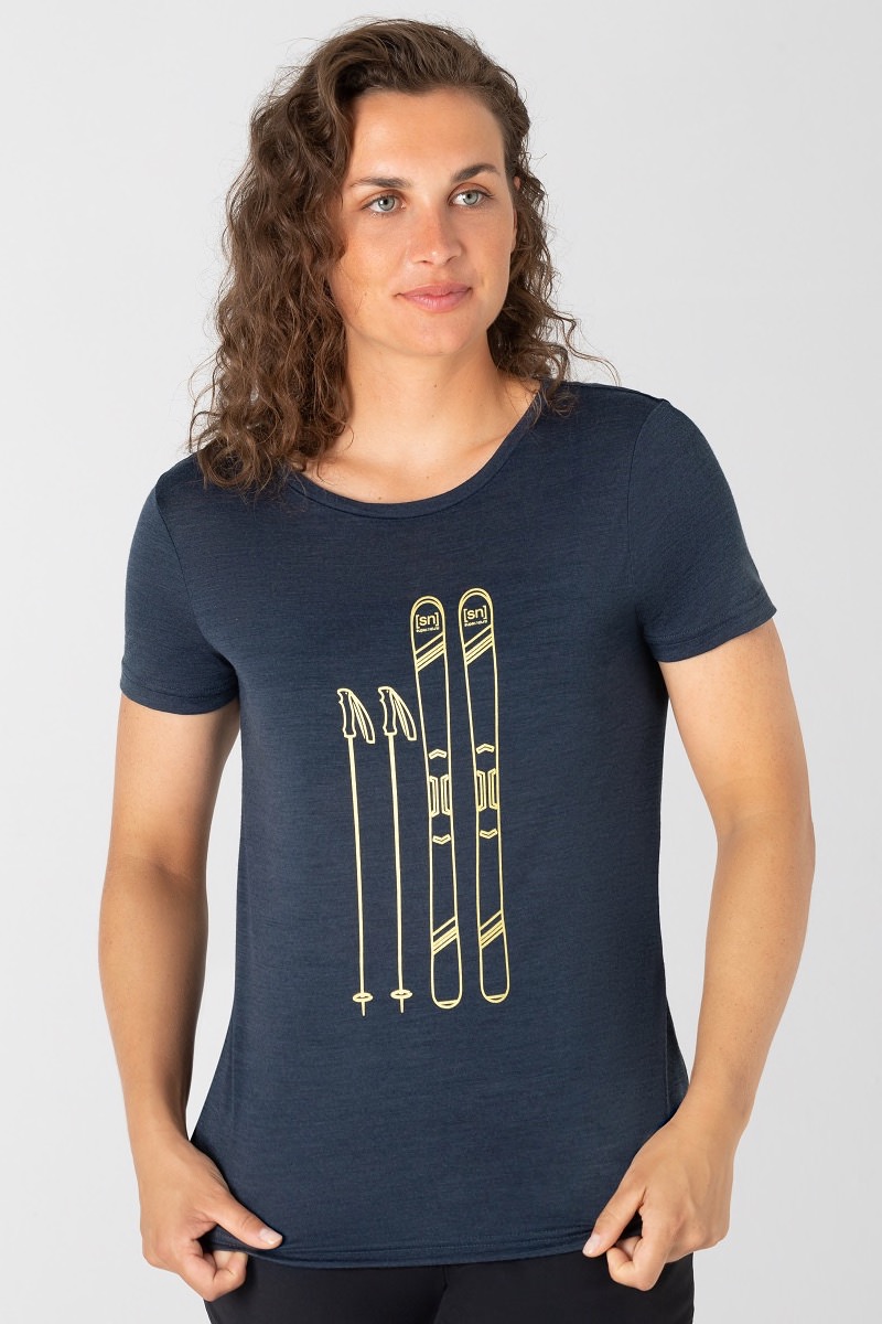 Frau trägt ein blaues Skiing Tee mit goldenem Ski- und Stock-Print.