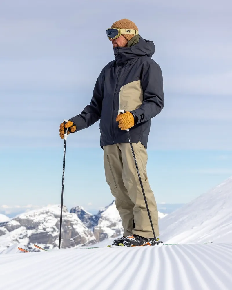 Ein Mann mit Skibrille und Mütze trägt die S-6 Ride Insulated Jacket Asphalt Seneca Rock beim Skifahren.