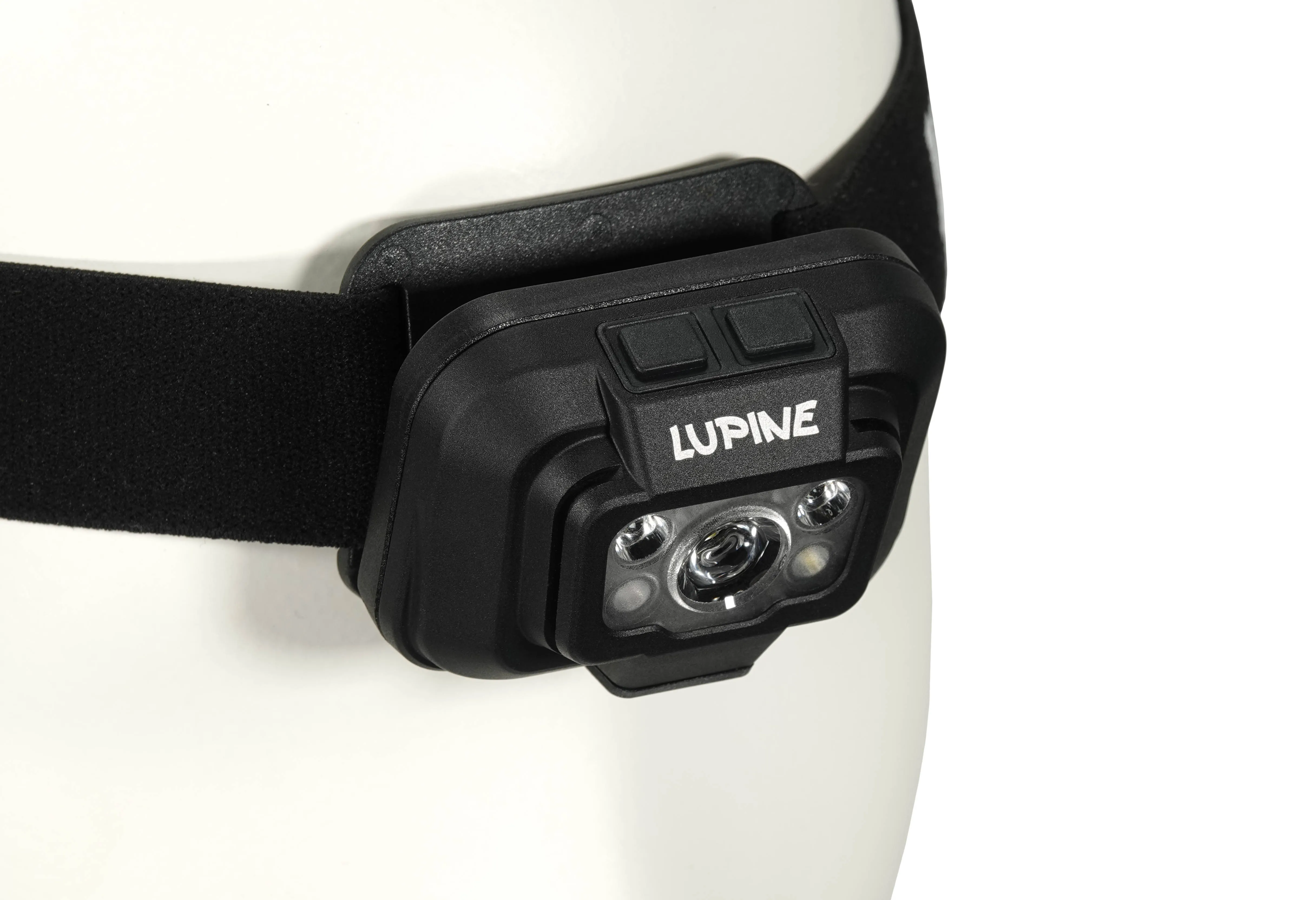 Nahaufnahme einer Penta Stirnlampe mit schwarzem Stirnband an einem weißen Kopf. "Lupine" Schriftzug.
