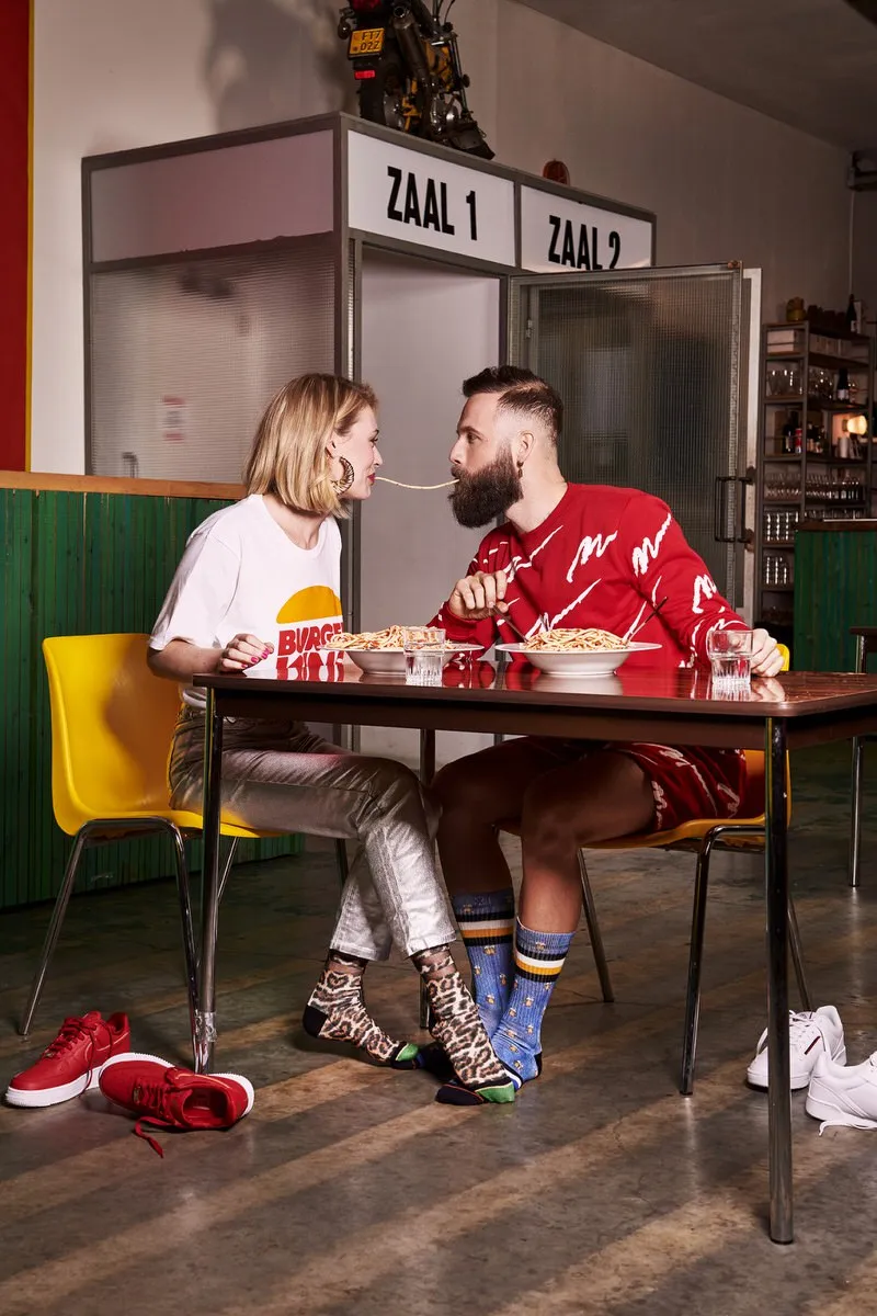 Ein Paar isst Spaghetti; er trägt XPOOOS Pint Luke Socken mit Bier-Motiv.