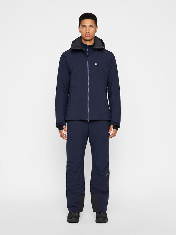J.Lindeberg Skimode Herren Ein Mann trägt navyfarbene J.Lindeberg Truulli Skihose und passende Jacke.
