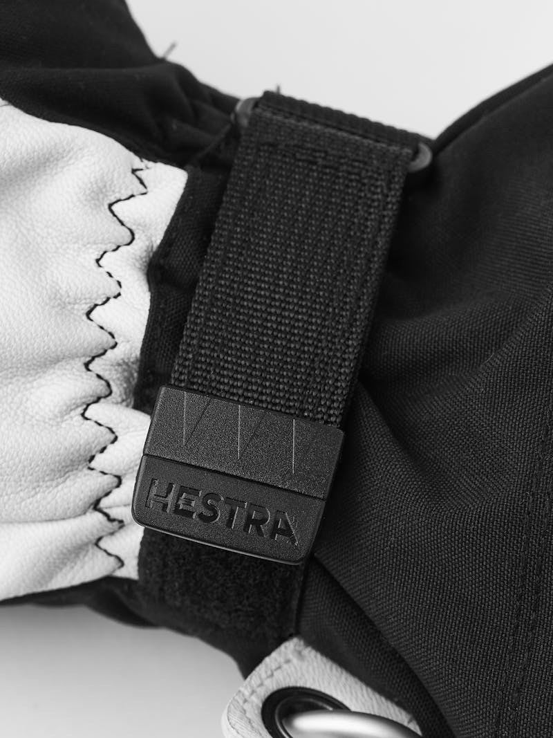 Hestra Army Leather Heli Ski Mitt Detailansicht des Hestra Army Leather Heli Ski Mitt, zeigt Leder, Stoff und den Markennamen auf dem Verschluss.