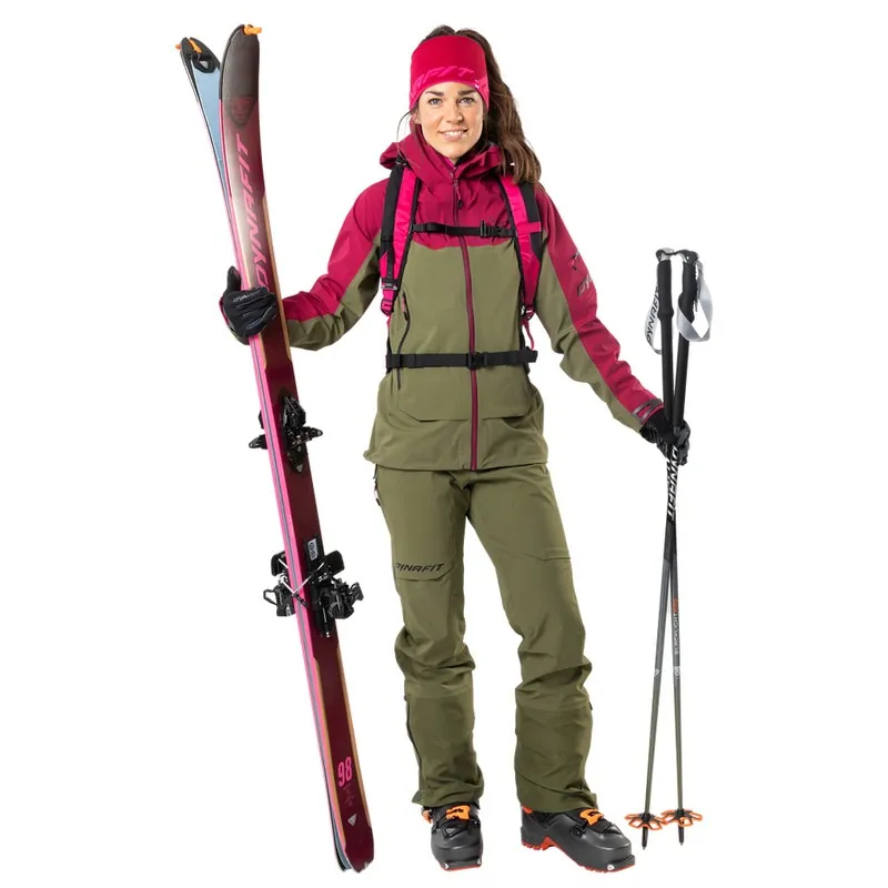 Frau in Beet Red Dynafit Beast Hybrid Jacke, Skiern und Stöcken, bereit für die Ski-Tour.