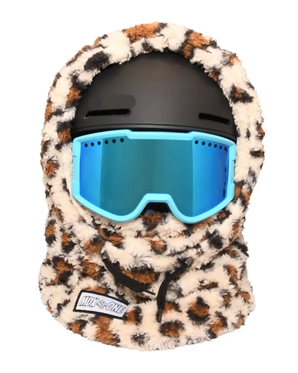 Flauschige Kinder-Sturmhaube in warmen Brauntönen mit Jaguar-Muster, über einem schwarzen Skihelm. Leuchtend hellblaue Skibrille mit verspiegelten Gläsern sitzt darüber. Soft-Plush bedeckt Kopf, Hals und Gesicht; schwarze Kordelzüge unten.
