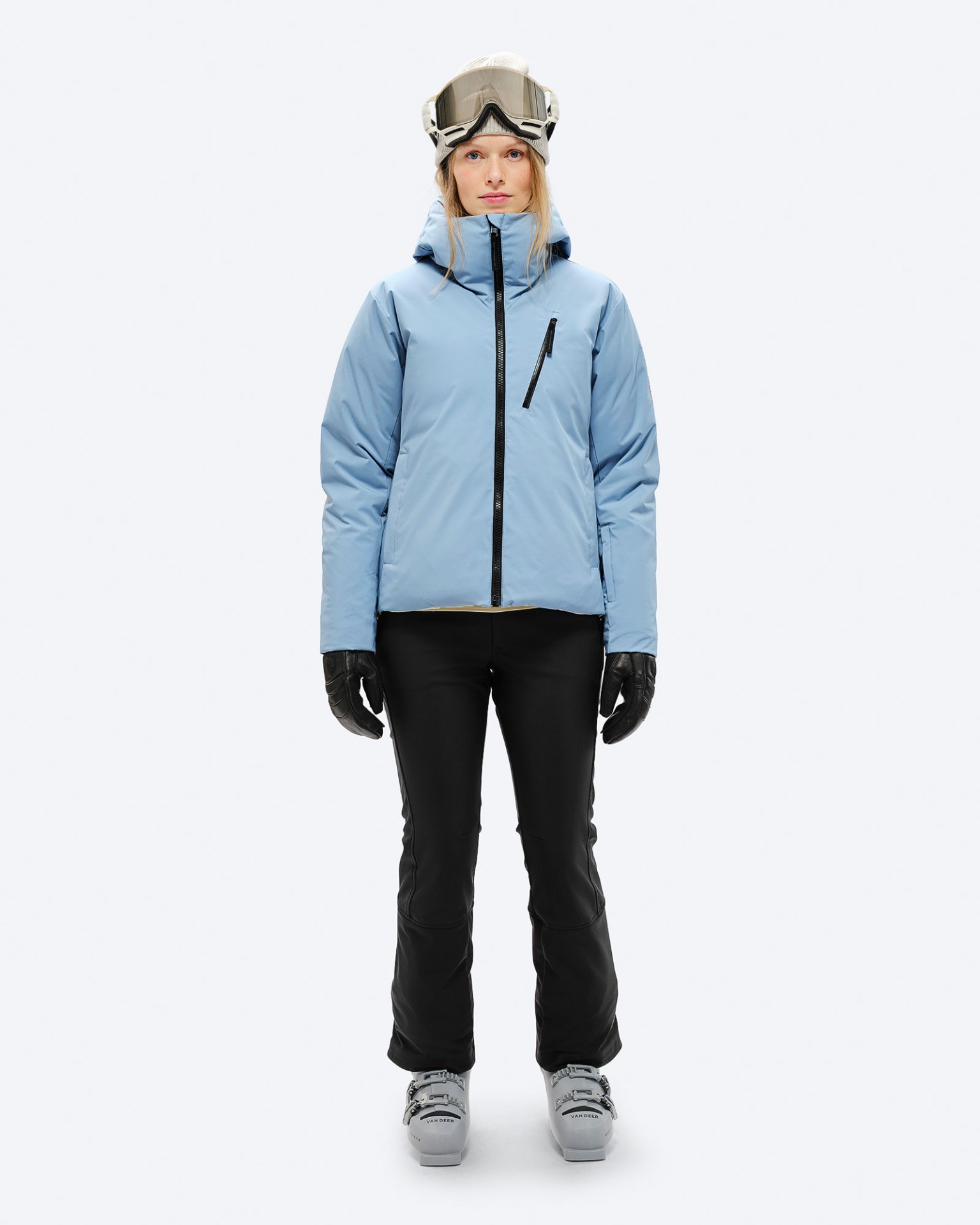 Person mit Skibrille, Daunenjacke in "Castle Wall", schwarzer Hose und Handschuhen, sowie Skischuhen.