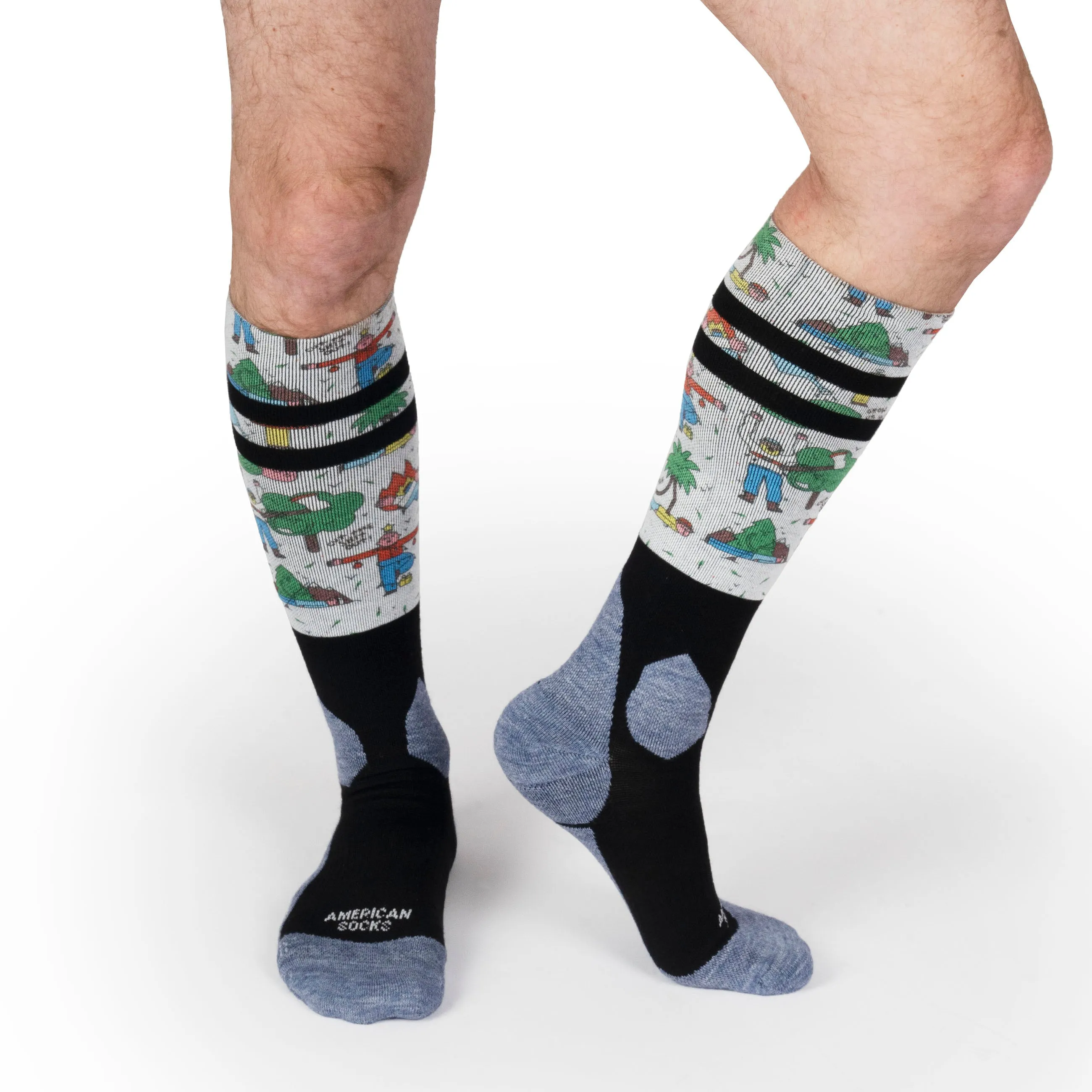 Beine mit "Leaf Me Alone" Snow Socks, grau, schwarz, Motiv mit Comicfiguren und Palmen.
