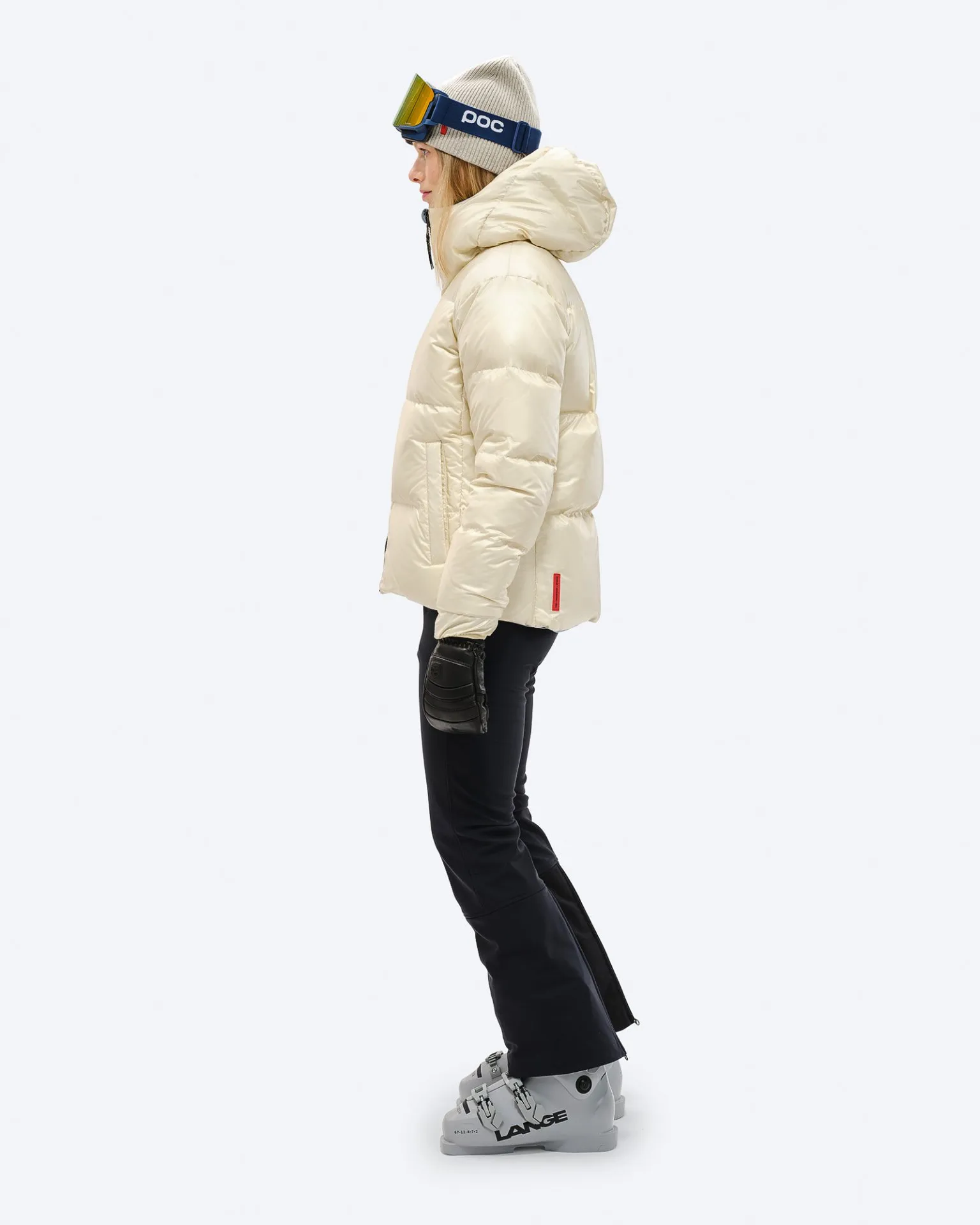 Person in Skikleidung, trägt eine Daunenjacke in Castle Wall Farbe, Mütze und Skibrille. Ski sind angezogen.
