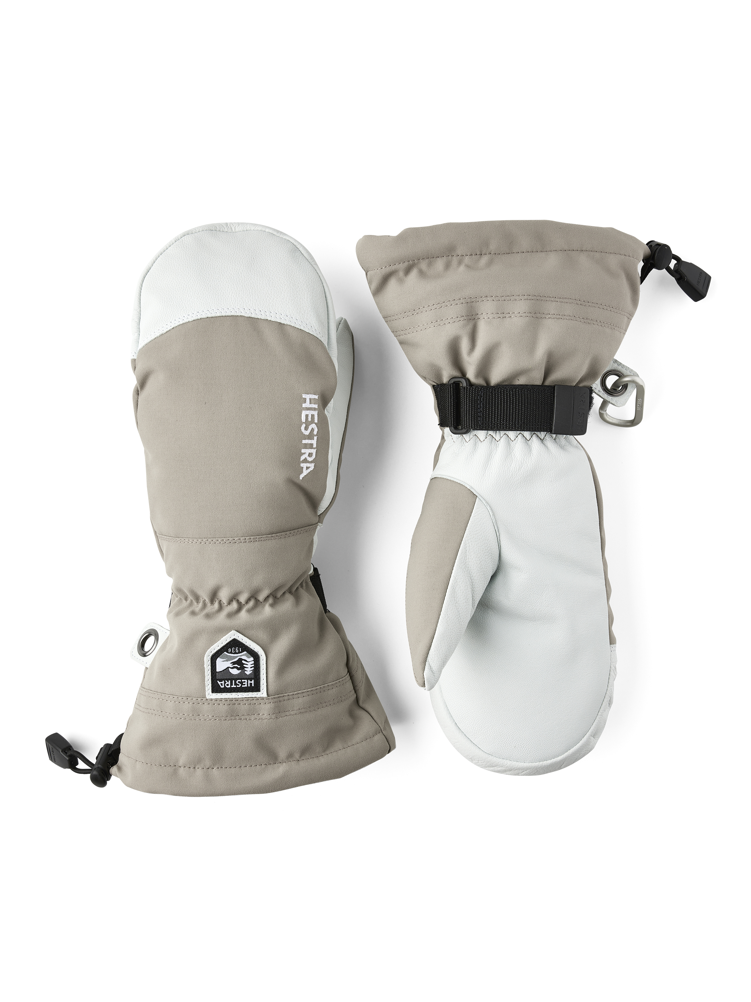 Zwei Hestra Army Leather Heli Ski Fäustlinge, beige und weiß, nebeneinander auf weißem Grund.