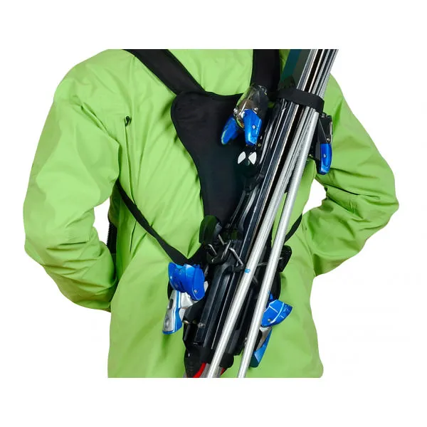 Person mit grünem Anorak trägt Ski mit dem Skiback wie einen Rucksack.