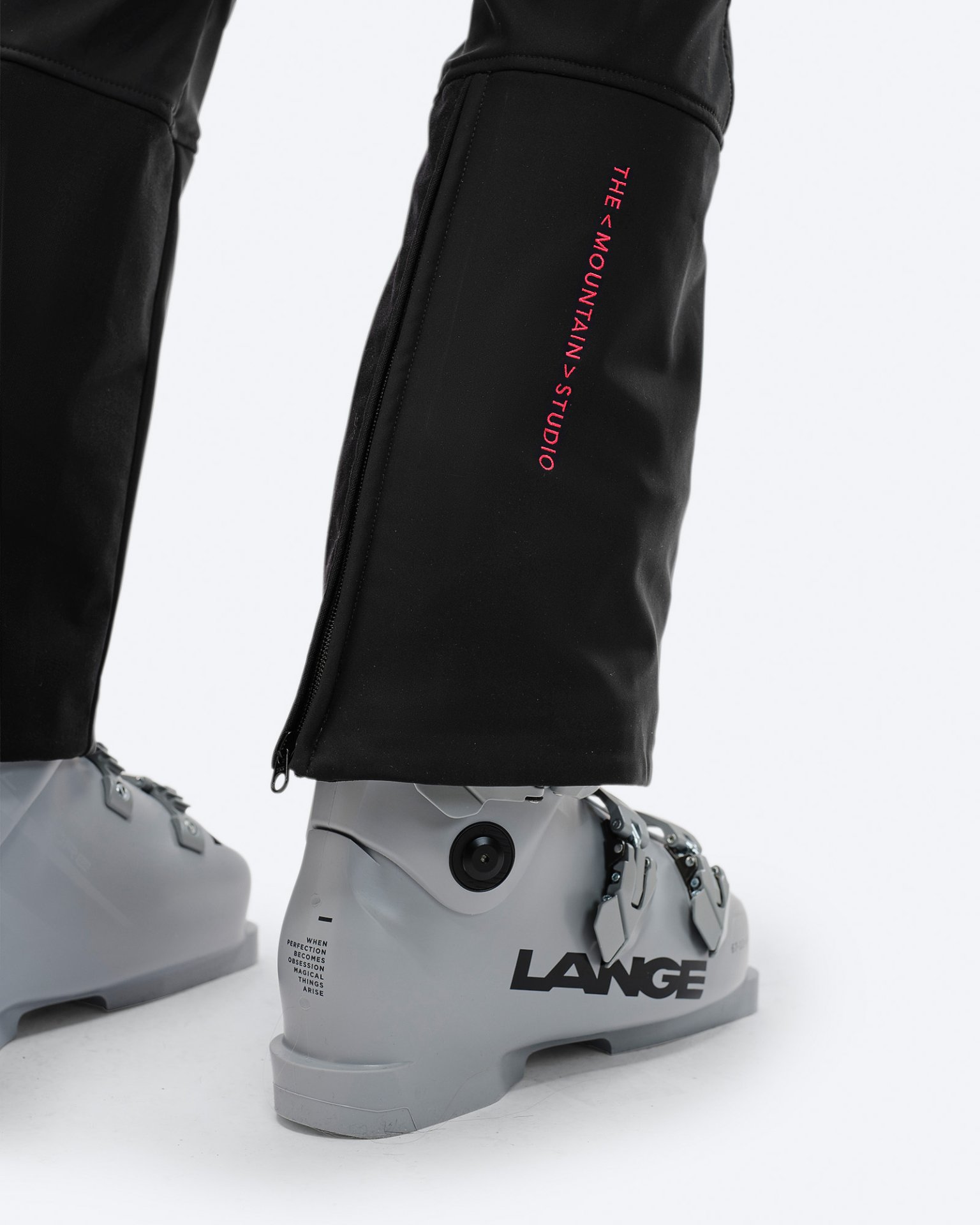 Detailaufnahme der schwarzen P-4 W 2L Stretch Ski Pants mit Ski-Schuh. Reißverschluss am Beinabschluss und Logo sichtbar.