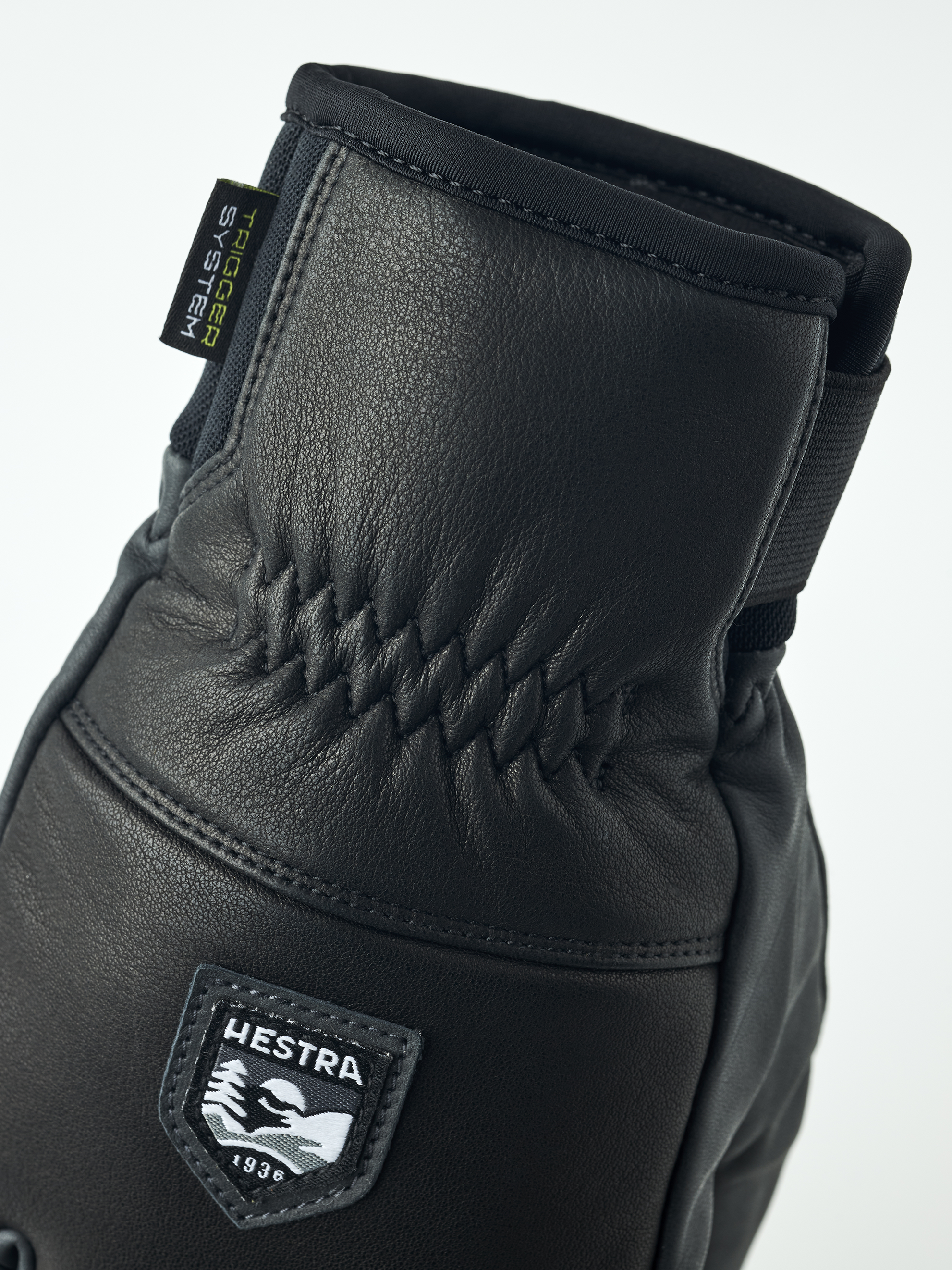 Detailaufnahme eines schwarzen Hestra Omni Trigger Handschuhs aus Leder mit Markenlogo.