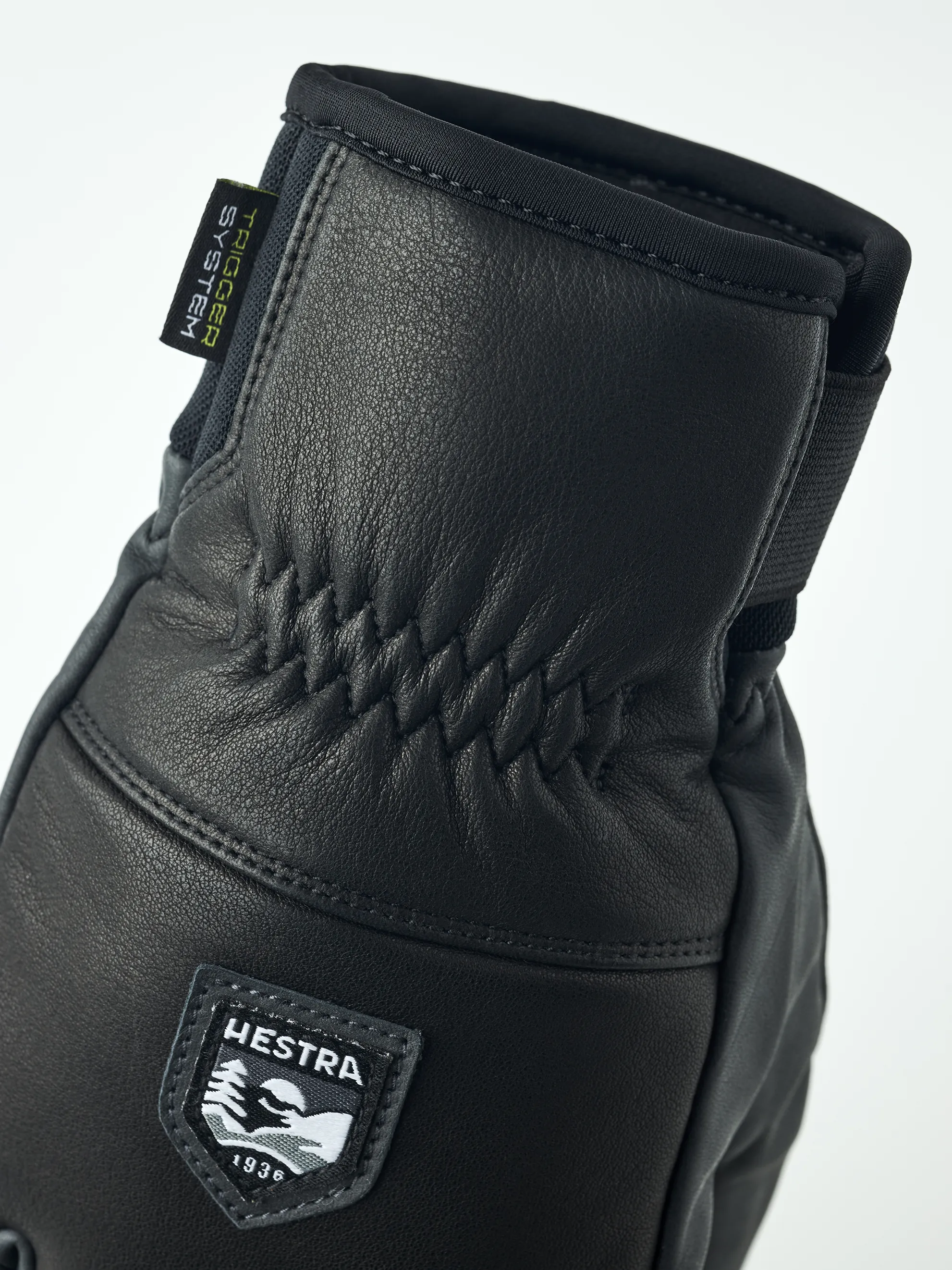 Detailaufnahme eines schwarzen Hestra Omni Trigger Handschuhs aus Leder mit Markenlogo.