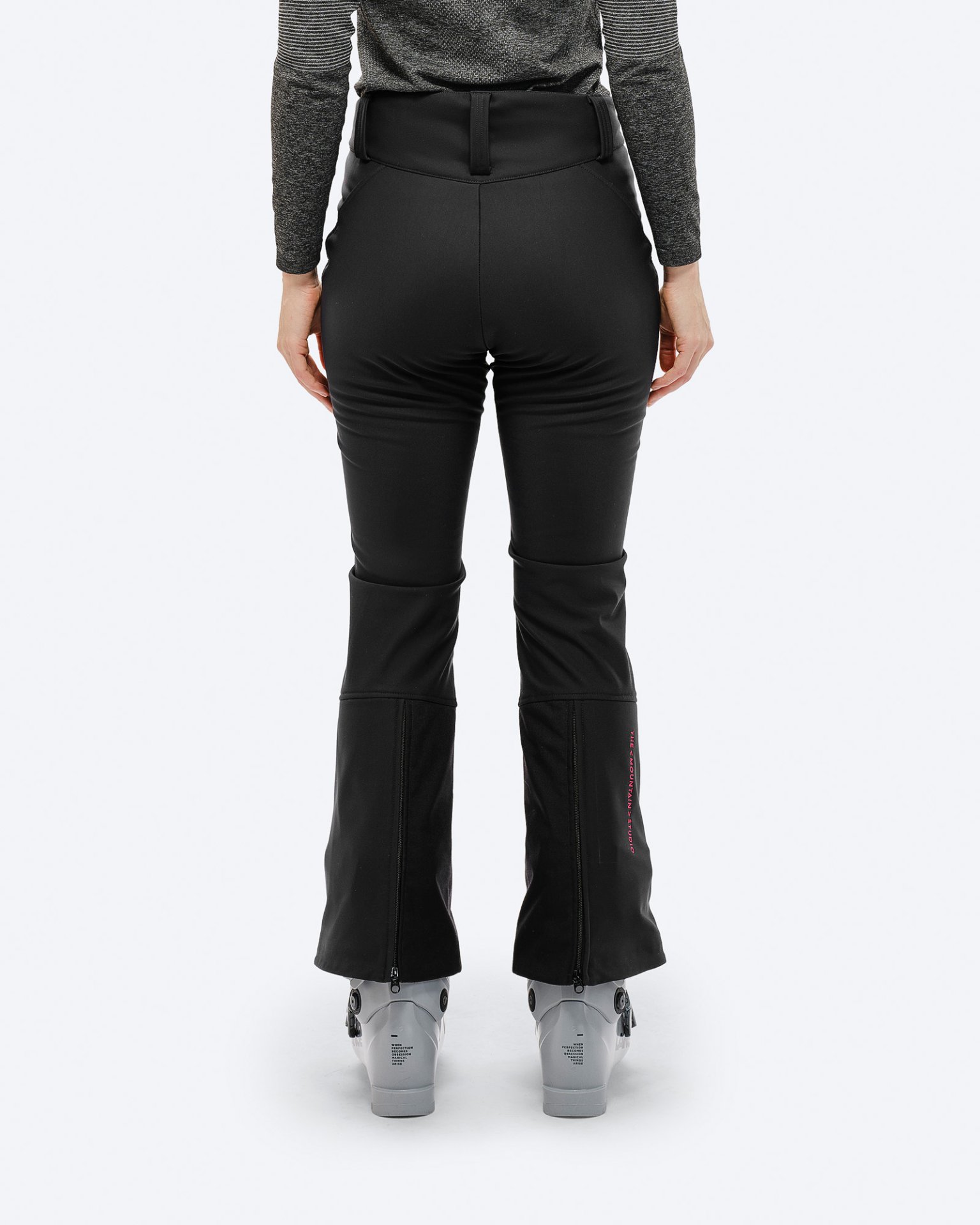 Rückansicht: Schwarze P-4 W 2L Stretch Ski Pants mit Skischuhen und pinkem Logo am Beinabschluss.