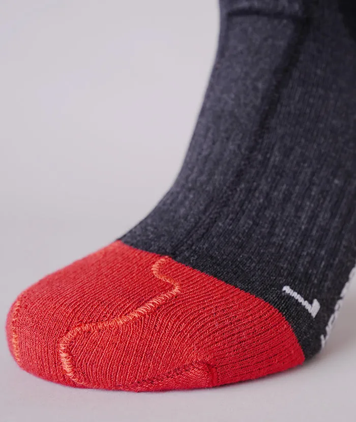 Nahaufnahme einer grauen Socke mit roter Spitze und verstärktem Bereich an der Fußsohle. Strickmuster sind sichtbar.