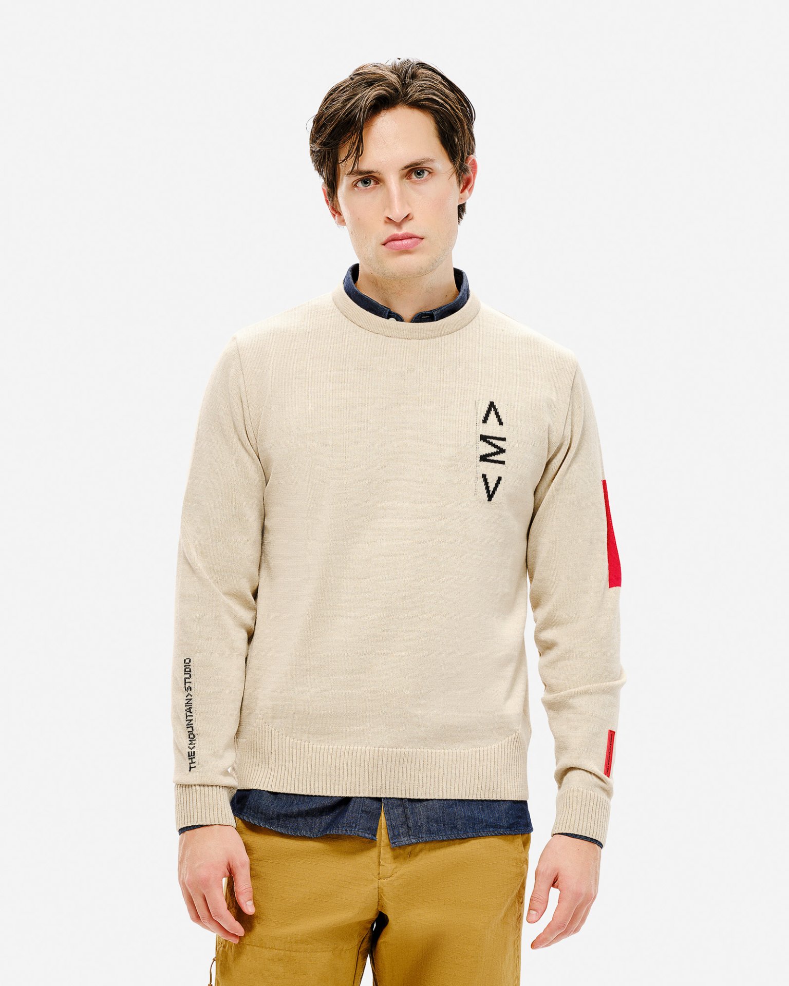 Mann trägt hellen K-3 ST Ski Sweater mit Rundhalsausschnitt, Logo und rotem Detail am Ärmel.