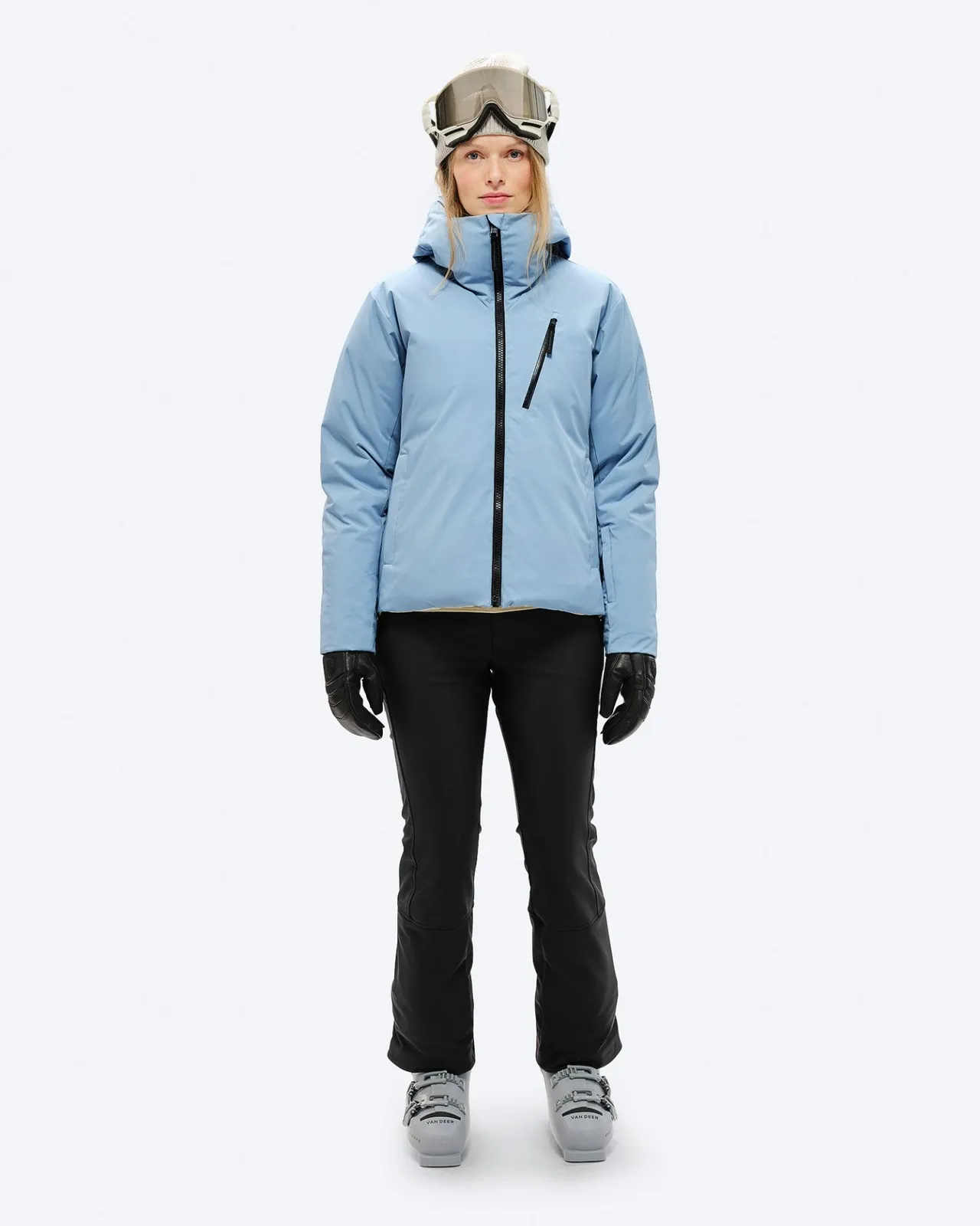 Person mit Skibrille, Daunenjacke in "Castle Wall", schwarzer Hose und Handschuhen, sowie Skischuhen.