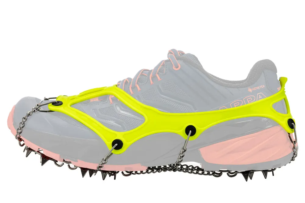 Schuh mit gelber Schuhkralle und Metallkette mit Spikes für Halt auf Eis und Schnee im Winter.