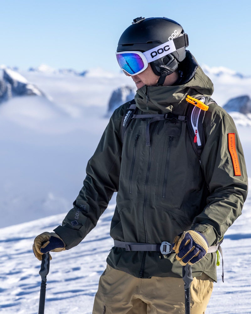 Skifahrer in grüner Z-2 HD GORE-TEX Pro Jacke vor verschneiter Bergkulisse.