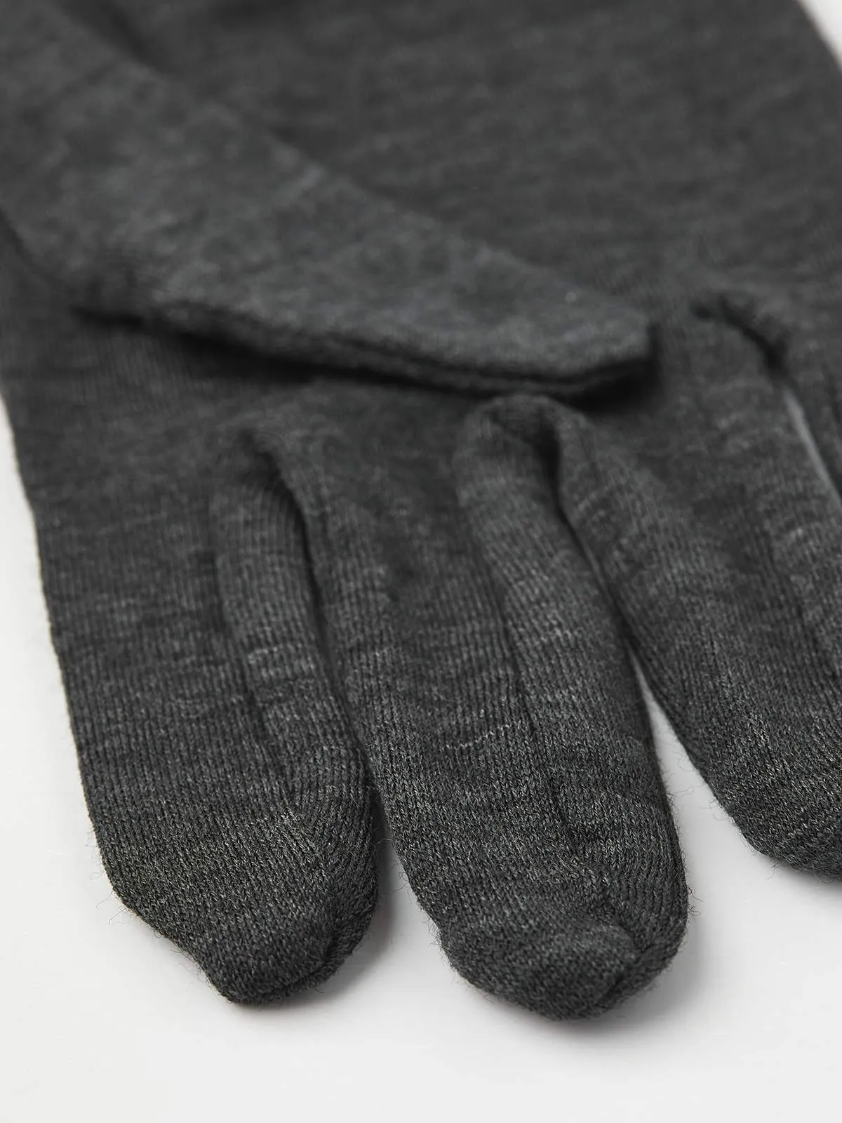 Nahaufnahme eines grauen Hestra Merino Wool Liner Active Handschuhs. Texturiertes Strickmuster sichtbar.