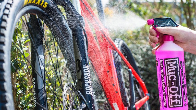 Fahrradreinigung mit Muc-Off Reinigung eines Fahrrads mit Muc-Off Nano Tech Reiniger aus rosa Sprühflasche. Fahrrad wird sauber gesprüht.