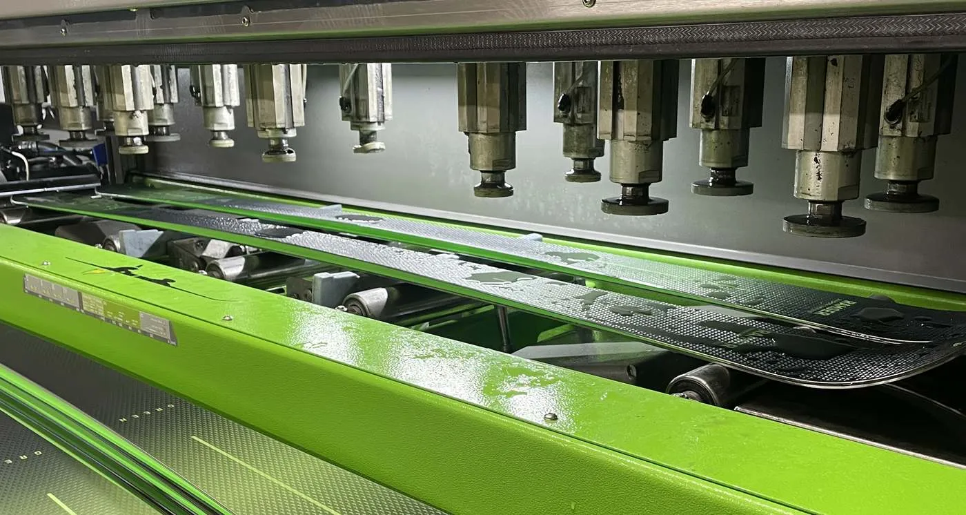 Ski laeuft in der Wintersteiger Mercury durch die Skiservice-Maschine in der Werkstatt von Ski-Shop Ramser