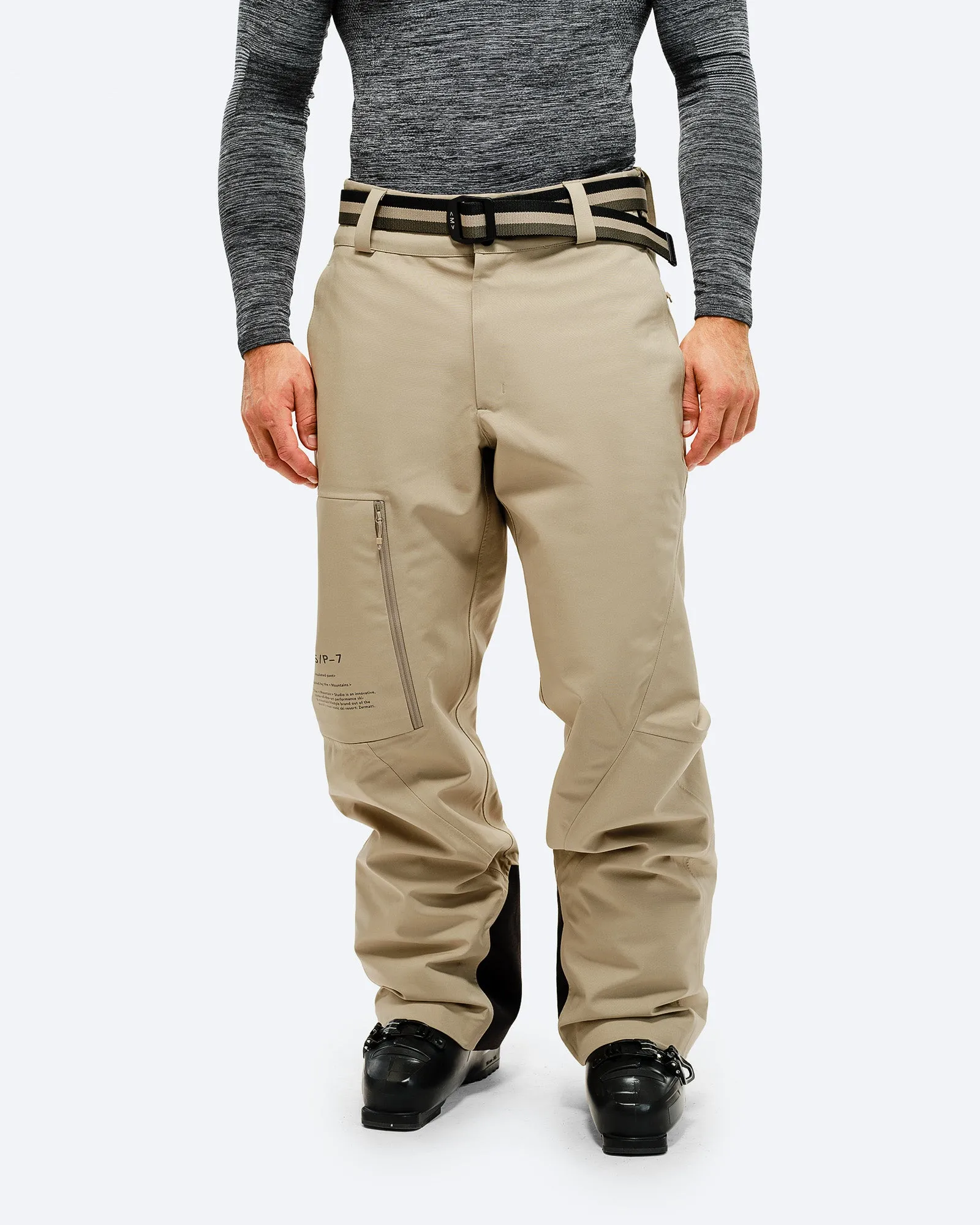 Person mit forest green Hose und Gürtel, stehend vor weißem Hintergrund.