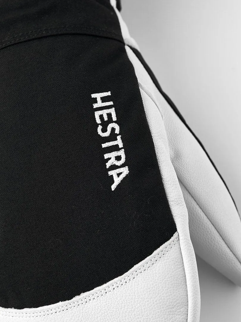 Nahaufnahme eines schwarzen Hestra-Handschuhs mit weißem Leder und dem weißen Schriftzug "HESTRA" auf der Oberseite.