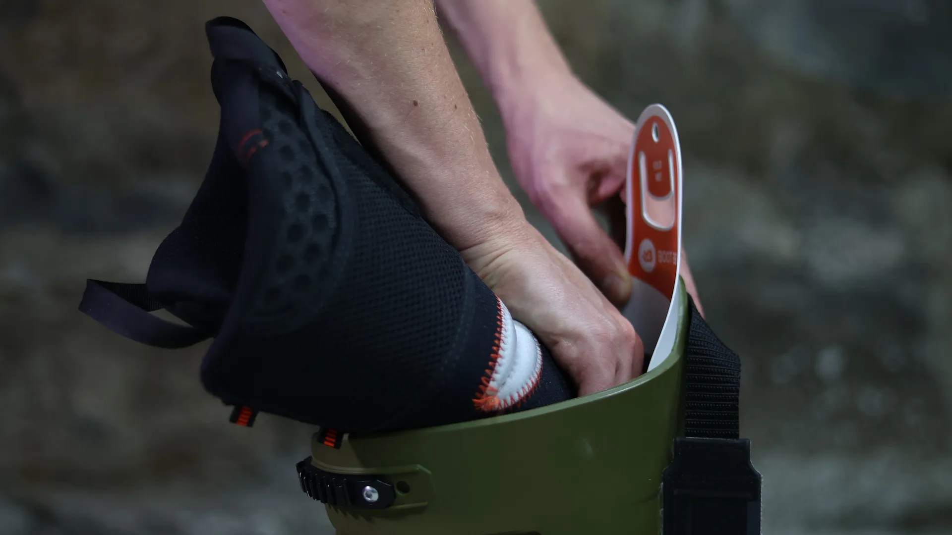 Nahaufnahme von Händen, die einen Save Liner in einen grünen Boot stecken. Der Liner ist schwarz mit weißen Details.