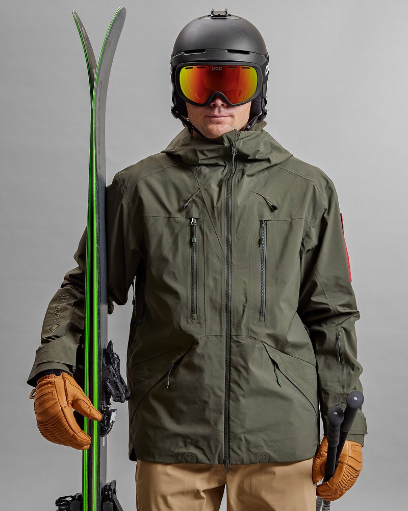 Person mit Ski, Helm und Brille trägt eine grüne Z-2 HD GORE-TEX Pro 3L Shell Jacket.